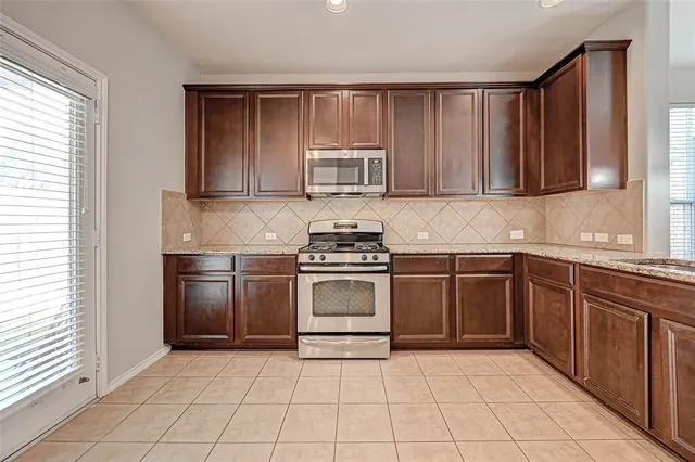 a kitchen with granite countertop a stove top oven cabinets and a sink