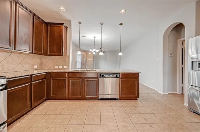 a large kitchen with granite countertop a sink a stove and a refrigerator