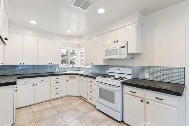 a kitchen with granite countertop white cabinets and white appliances