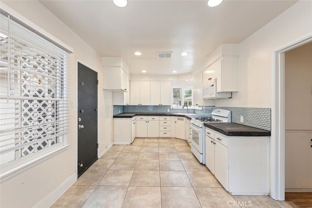 5663 Osburn Place Riverside, CA 92506 - Photo 10 of 38 a large white kitchen with granite countertop a sink a stove a refrigerator and white cabinets