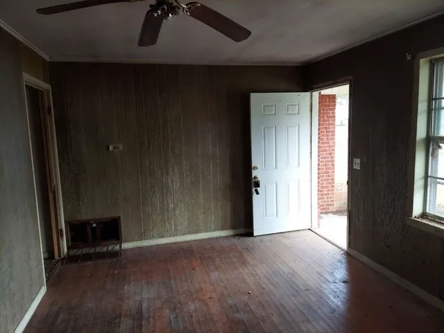 an empty room with wooden floor and windows