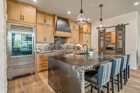 a kitchen with kitchen island granite countertop a table chairs sink and cabinets