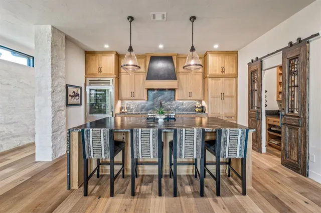 a kitchen with stainless steel appliances kitchen island granite countertop a dining table chairs and granite counter tops