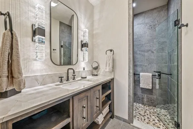 a bathroom with a granite countertop sink a mirror and shower