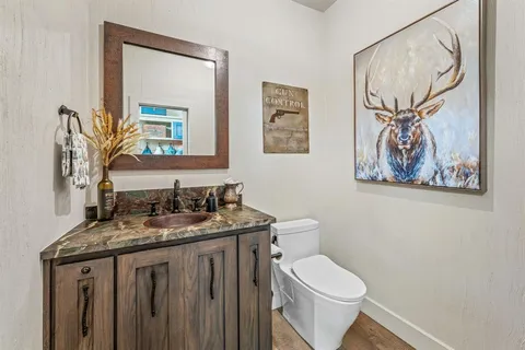 a bathroom with a granite countertop toilet a sink and a mirror
