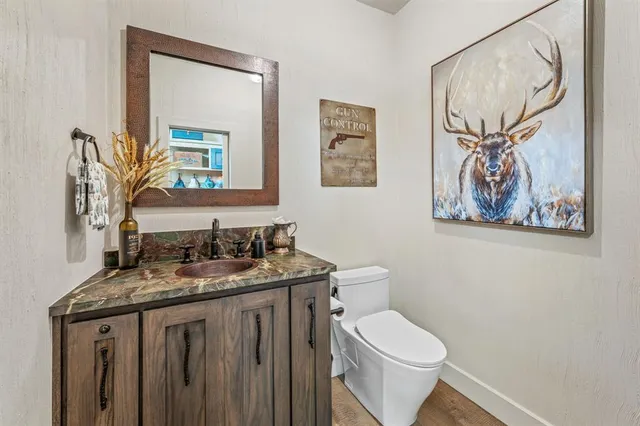 a bathroom with a granite countertop toilet a sink and a mirror