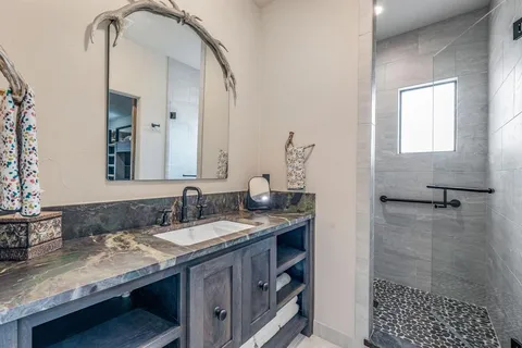 a bathroom with a granite countertop sink a mirror and shower