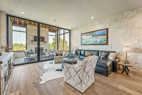 a living room with furniture large window and wooden floor