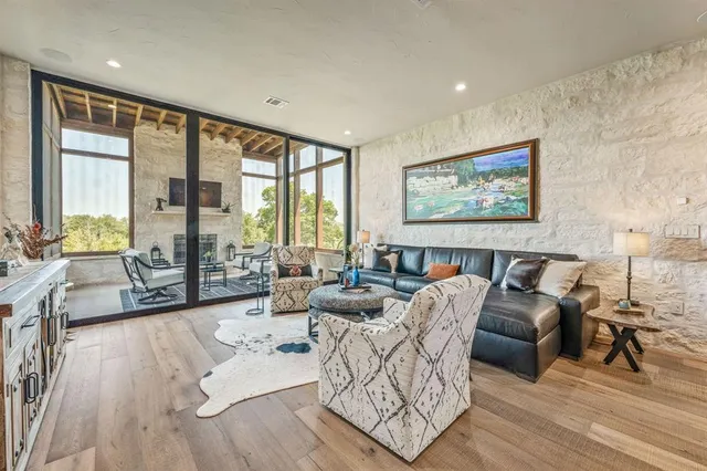 a living room with furniture large window and wooden floor