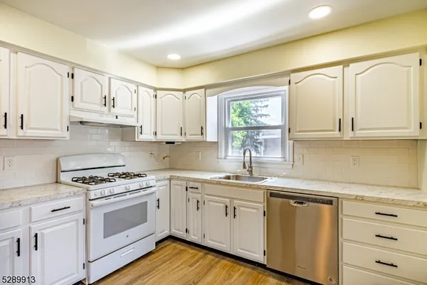 a kitchen with granite countertop white cabinets and white appliances