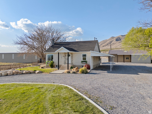 115 East 1600th Street North Santaquin, UT 84655 - Photo 37 of 52 White brick exterior with a dark shingle roof, featuring a covered front porch and a gravel driveway