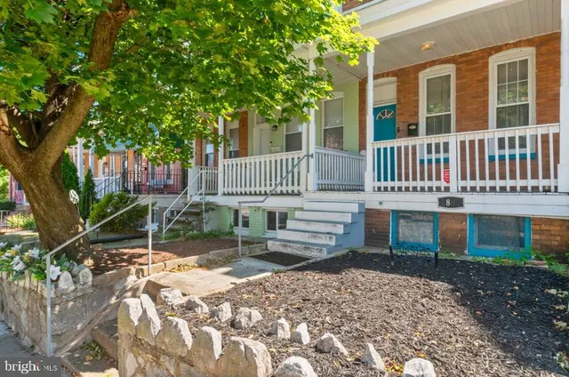 a front view of a house with a yard tree and wooden fence