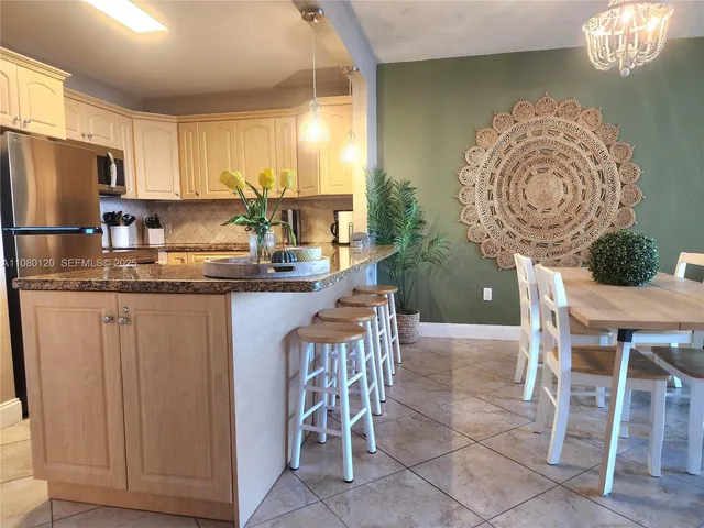 a kitchen with kitchen island granite countertop a sink a stove a dining table and chairs