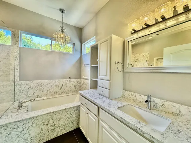 a bathroom with a granite countertop sink mirror and bathtub