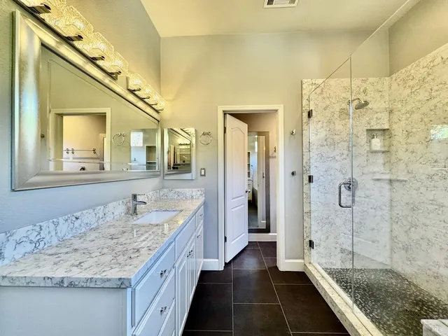 a bathroom with a granite countertop sink a mirror and shower