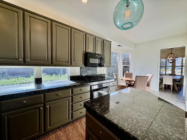 a kitchen with granite countertop wooden cabinets a stove and a sink