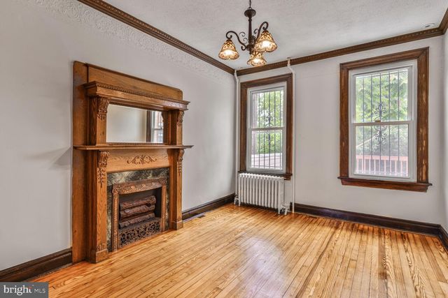 a view of an empty room with wooden floor fireplace and a window