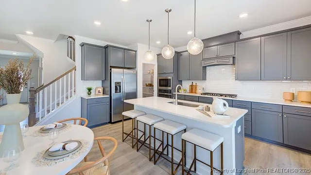 a kitchen with stainless steel appliances kitchen island granite countertop a table chairs and a refrigerator