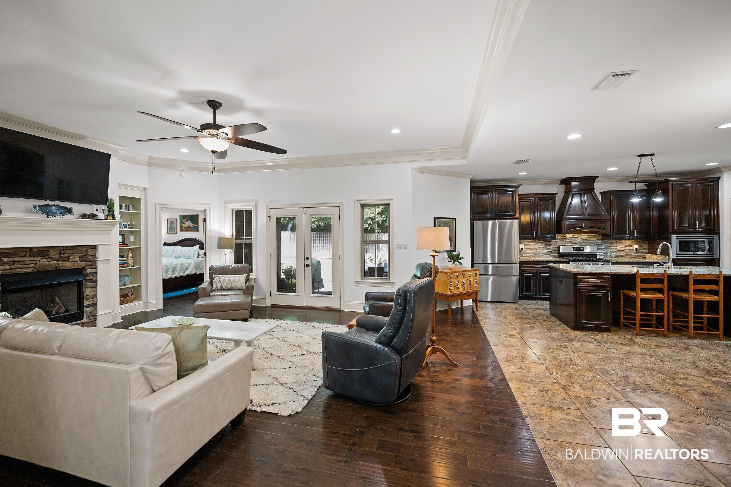 313 Pecan Ridge Boulevard Fairhope, AL 36532 - Photo 27 of 51 Spacious living area featuring a stone-faced fireplace with a white mantle, built-in shelving, wood-finish flooring, and French doors leading to exterior