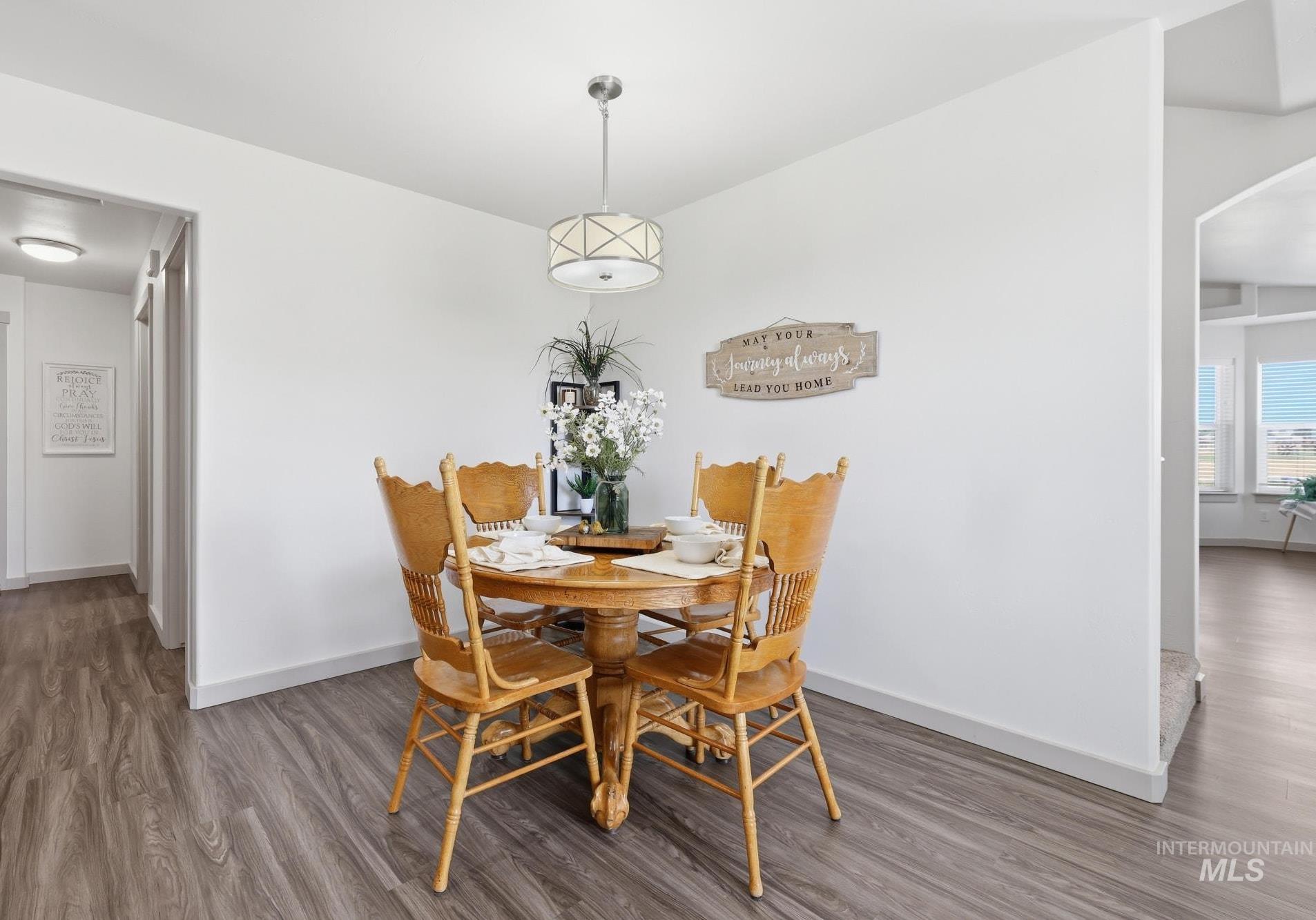 178 Syringa Loop Shoshone, ID 83352 - Photo 8 of 35 Bright dining area featuring a round wood table with rush-seat chairs, pendant lighting with geometric detailing, and wood-finish flooring throughout