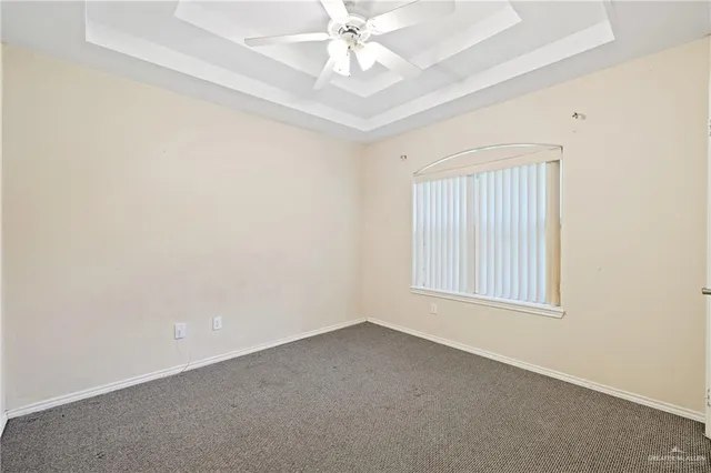 an empty room with a chandelier fan and windows