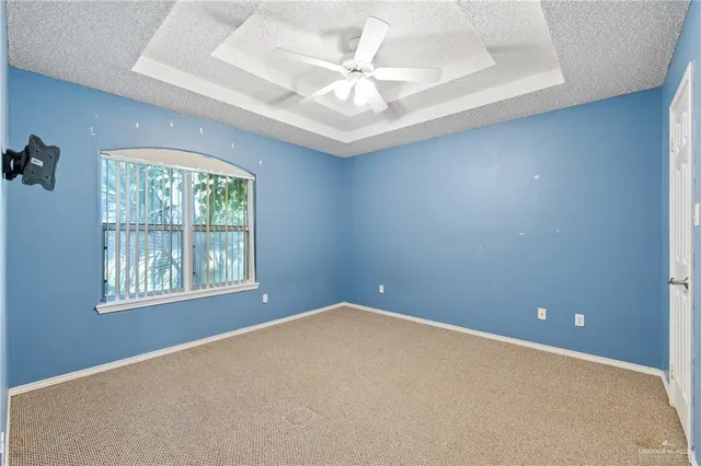 an empty room with windows and ceiling fan