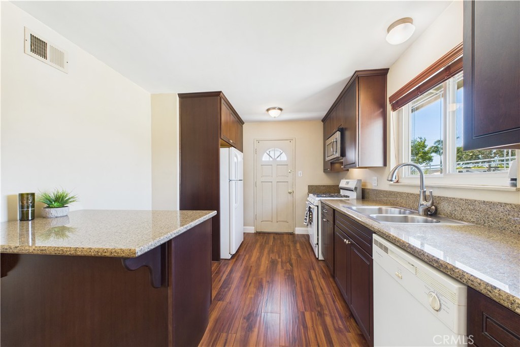 10002 St Elizabeth Circle Cypress, CA 90630 - Photo 6 of 35 a large kitchen with granite countertop a sink dishwasher stove and refrigerator