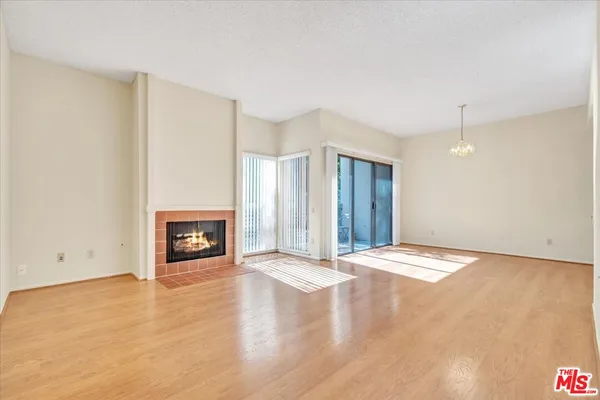 a view of an empty room with wooden floor and a fireplace