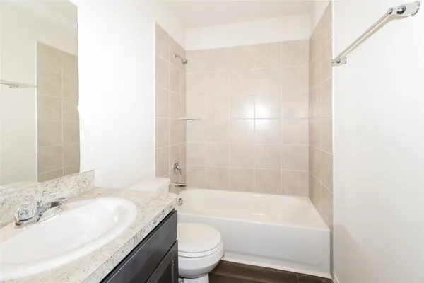 a bathroom with a bathtub shower sink vanity mirror and toilet