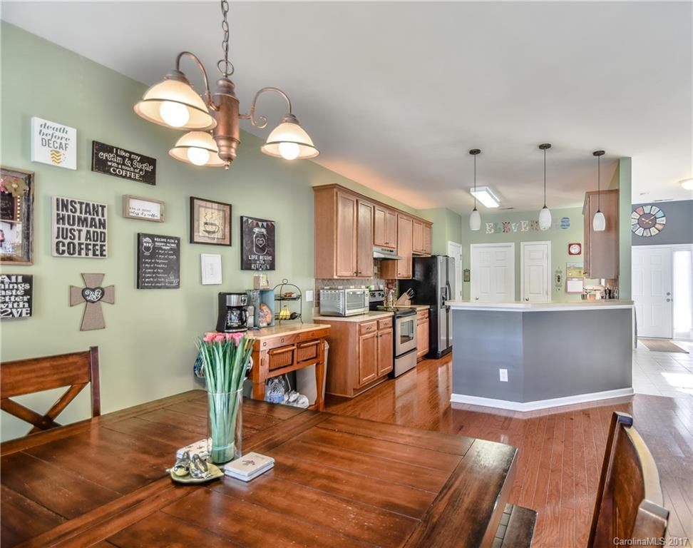 225 Mott Road Mooresville, NC 28115 - Photo 12 of 24 a dining room with wooden floor a chandelier a glass table and chairs