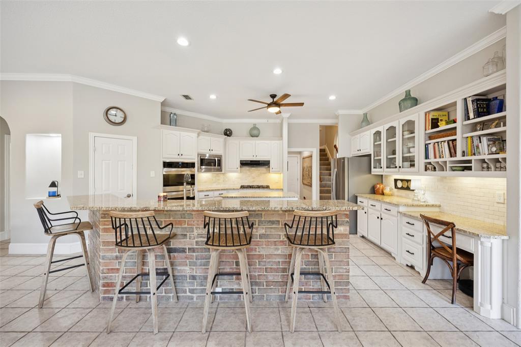 3611 Skinner Road Midlothian, TX 76065 - Photo 9 of 40 a kitchen with stainless steel appliances kitchen island granite countertop a dining table chairs and white cabinets