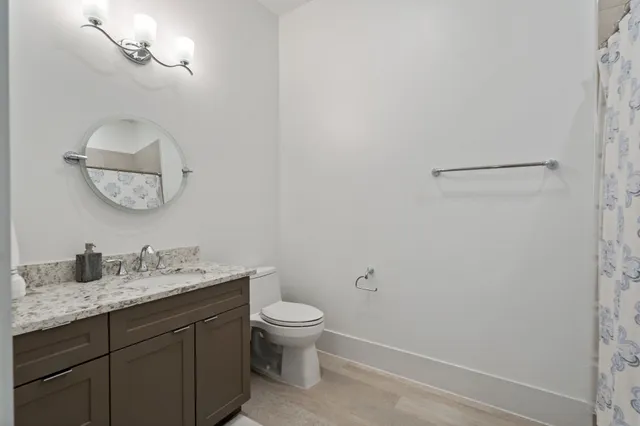 a bathroom with a granite countertop toilet sink and mirror