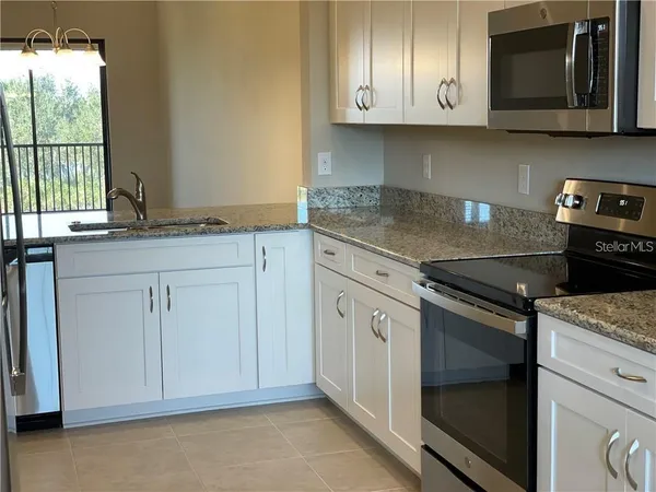 a kitchen with granite countertop white cabinets and black appliances