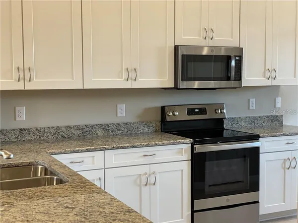 a kitchen with stainless steel appliances granite countertop a sink stove and microwave