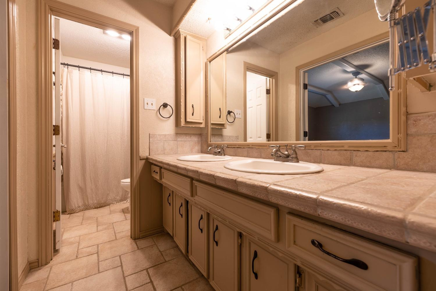 4522 79th Street Lubbock, TX 79424 - Photo 11 of 14 a bathroom with a granite countertop sink and a mirror