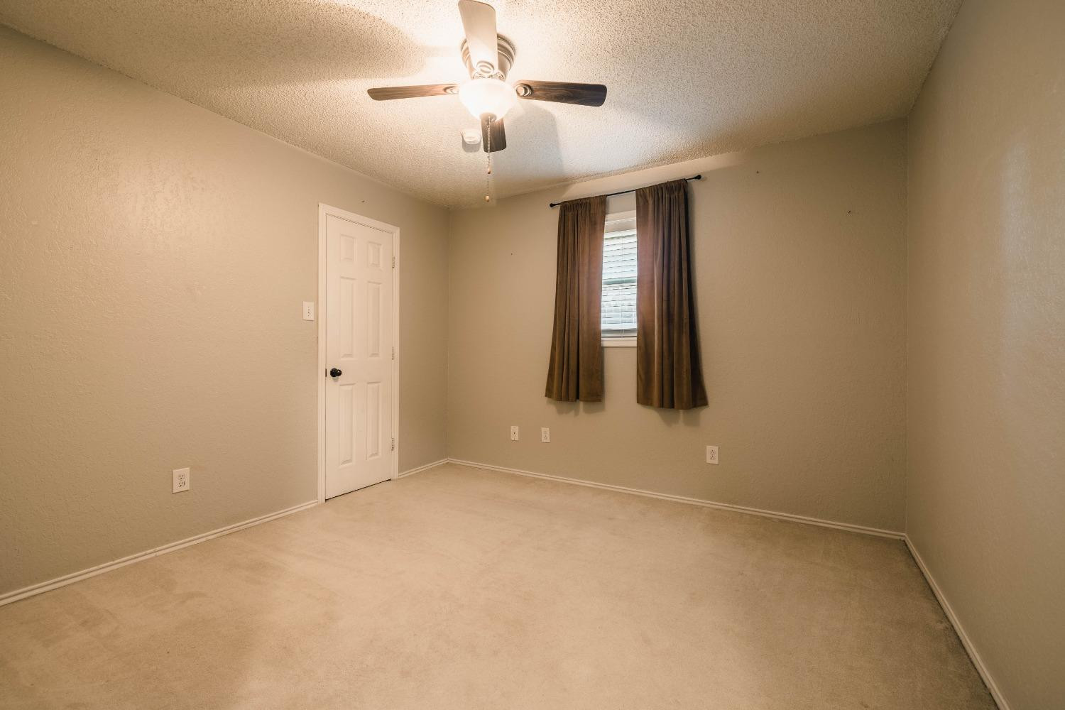 4522 79th Street Lubbock, TX 79424 - Photo 8 of 14 an empty room with chandelier fan and windows