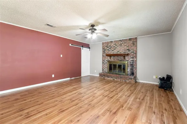 a view of an empty room with wooden floor fireplace and a window