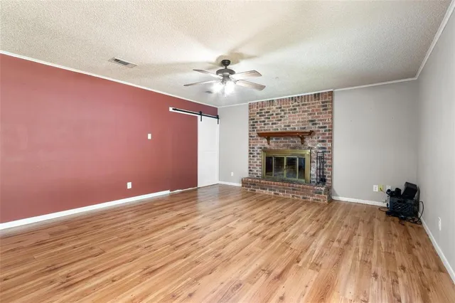 a view of an empty room with wooden floor fireplace and a window