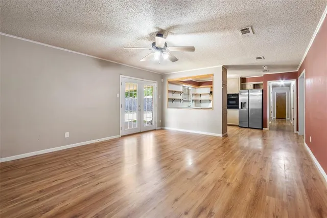 a view of an empty room with window and wooden floor