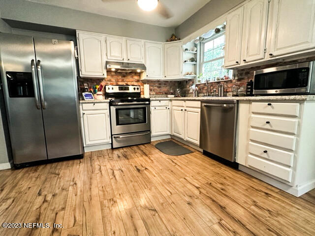 1504 Raiford Road Starke, FL 32091 - Photo 6 of 24 a kitchen with granite countertop a sink cabinets stainless steel appliances and a window