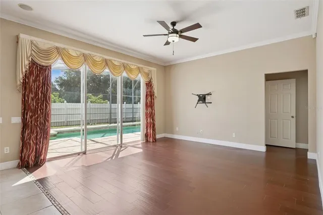 a view of empty room with wooden floor and fan