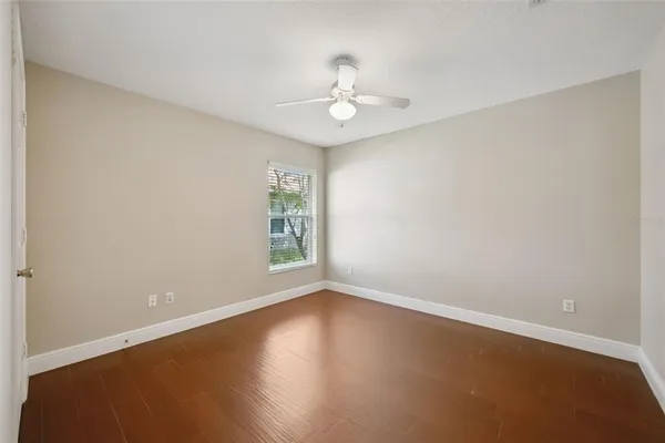 an empty room with wooden floor chandelier fan and windows