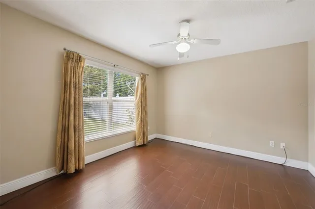an empty room with wooden floor fan and windows
