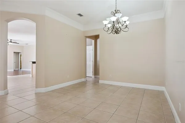 a view of an empty room with chandelier and bathroom