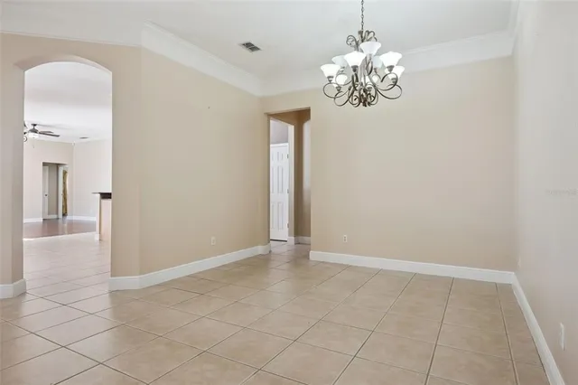 a view of an empty room with chandelier and bathroom