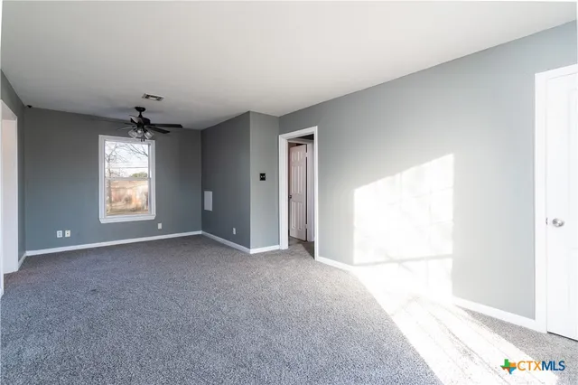 an empty room with windows and chandelier fan
