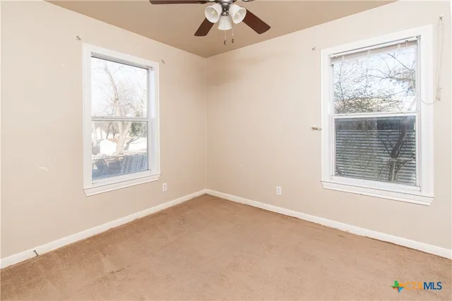 an empty room with a window and a ceiling fan
