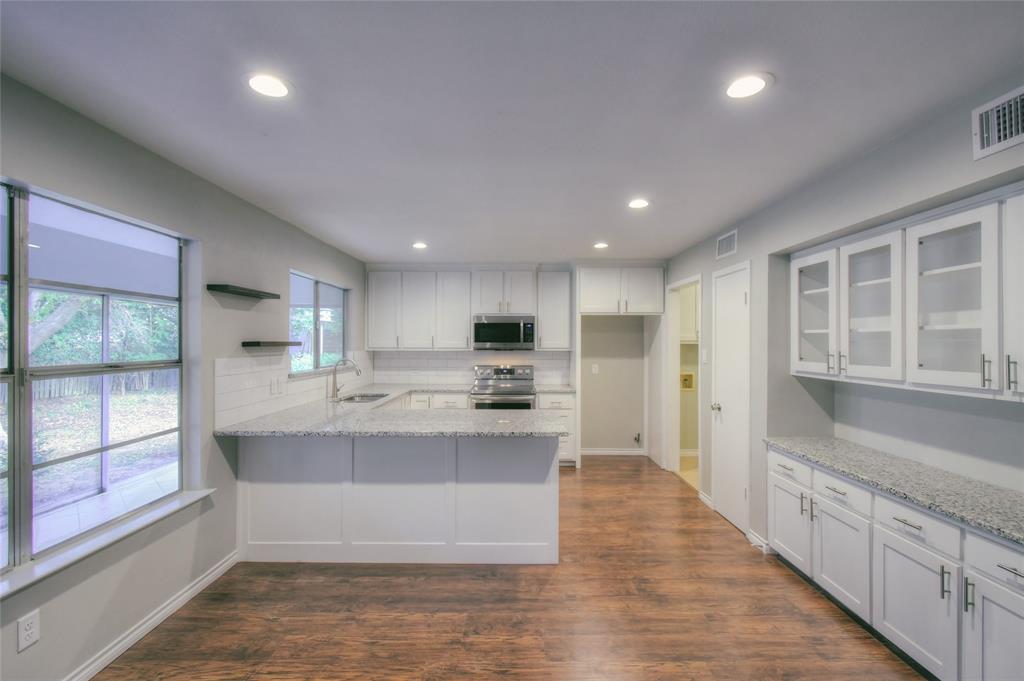 a large white kitchen with kitchen island a sink appliances counter top space and a large window