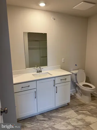 a bathroom with a granite countertop toilet sink and mirror