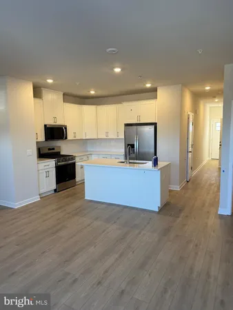 a large kitchen with stainless steel appliances kitchen island a large counter top and a wooden floor